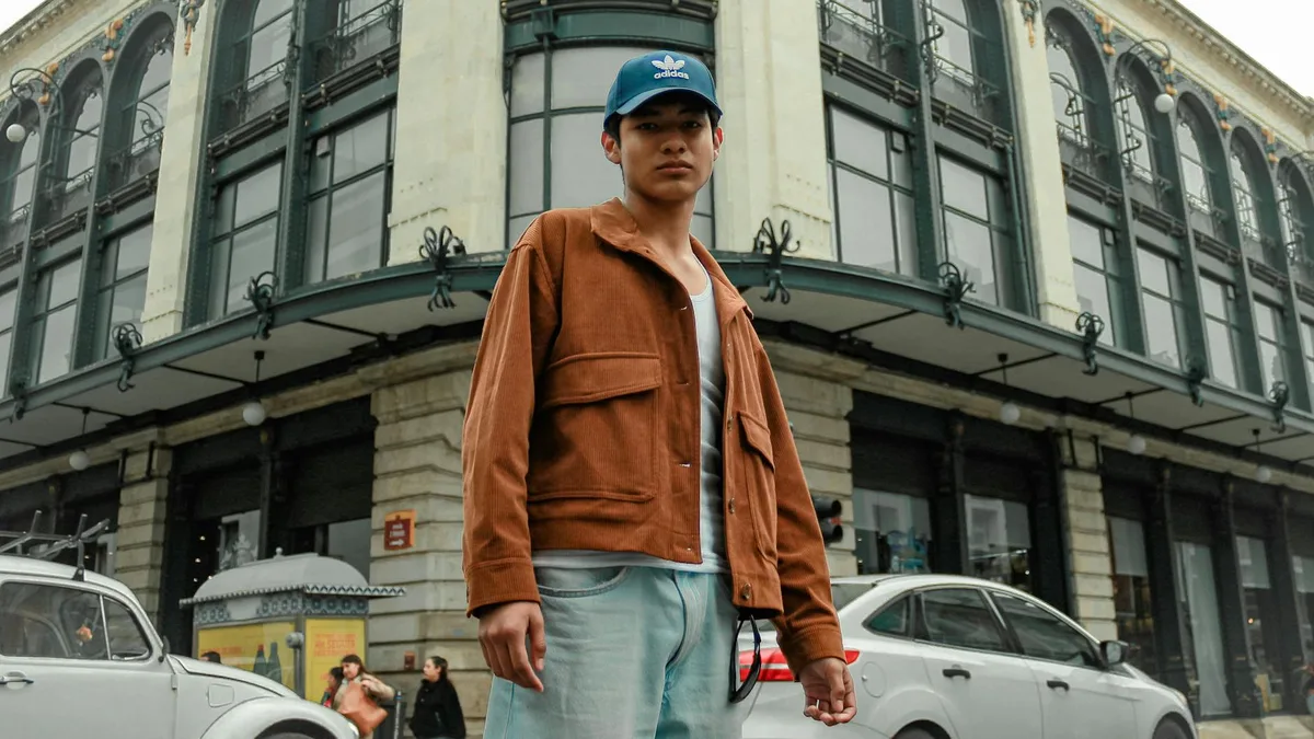 Giovane uomo in giacca marrone in posa sicura in strada urbana, atmosfera moderna