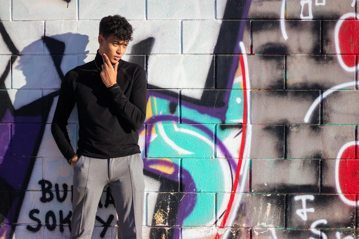 Stylischer junger Mann vor Graffiti-Wand in Valencia, Spanien