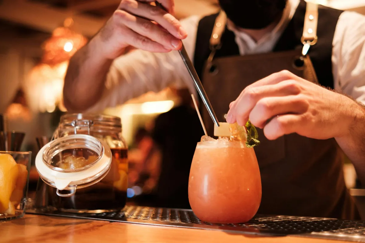 Bartender che prepara un cocktail alla frutta rinfrescante con precisione