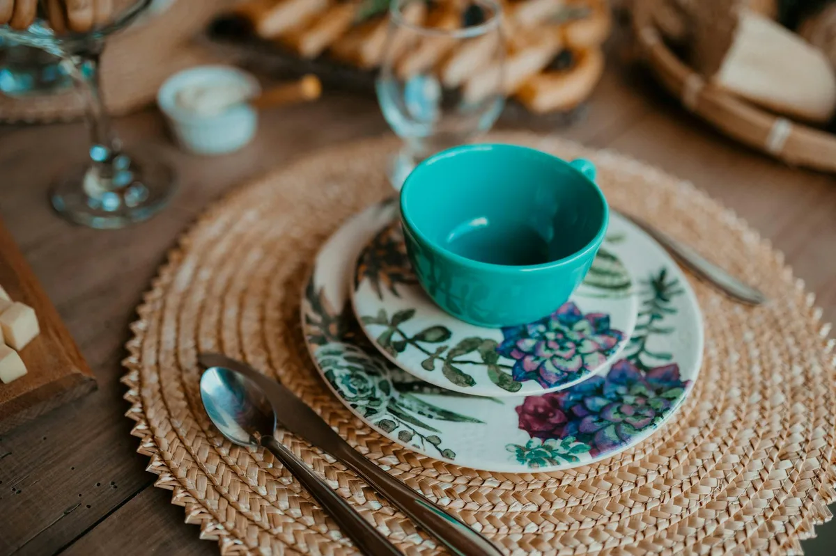 Table dressée avec assiettes fleuries et tasse turquoise pour un repas cosy