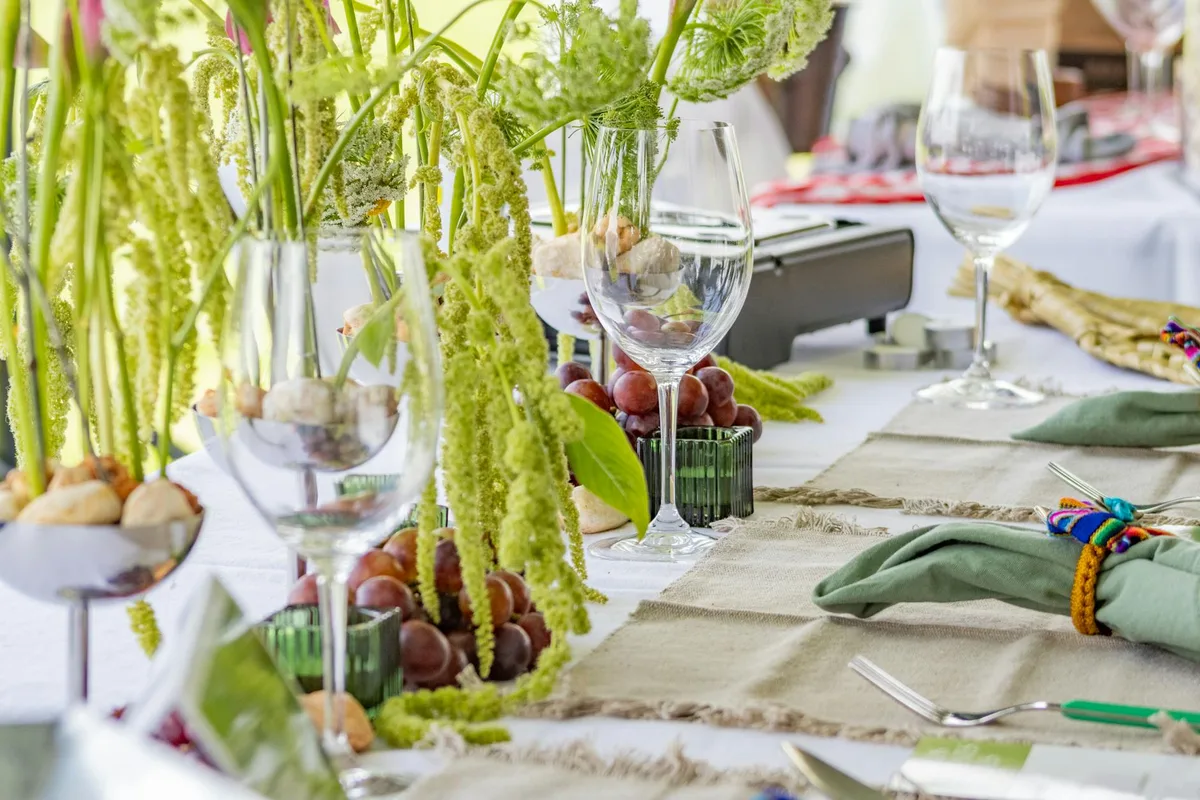 A beautifully arranged table setting featuring lush green foliage and grapes, perfect for elegant events.