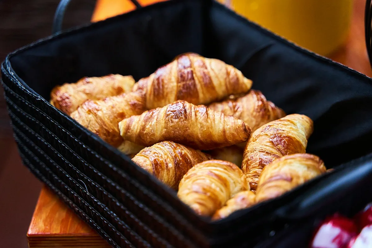 Close de croissants frescos em cesta preta para café da manhã ou brunch