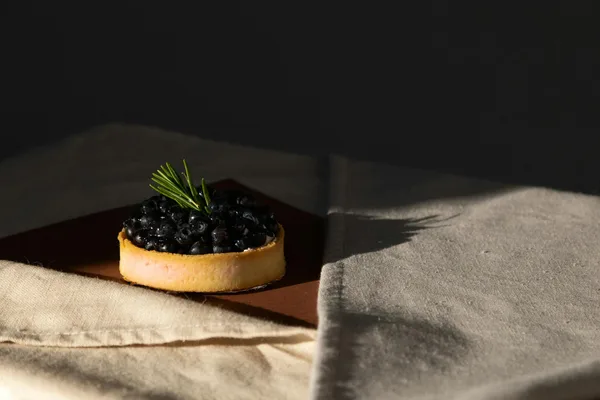 Tart ai mirtilli su stoffa con illuminazione soffusa, food photography