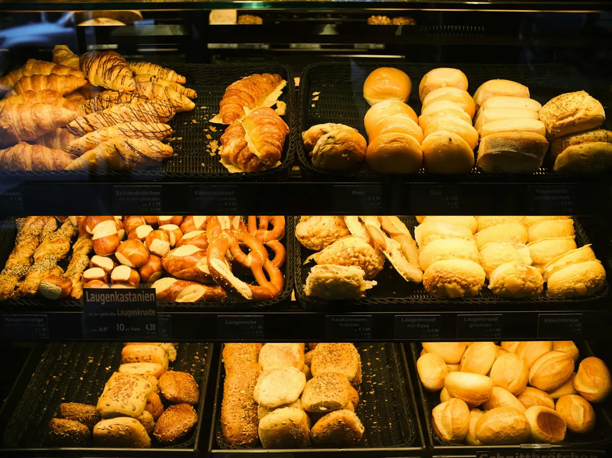 Varietà di pane, panini e pasticceria freschi esposti in una vetrina di panetteria