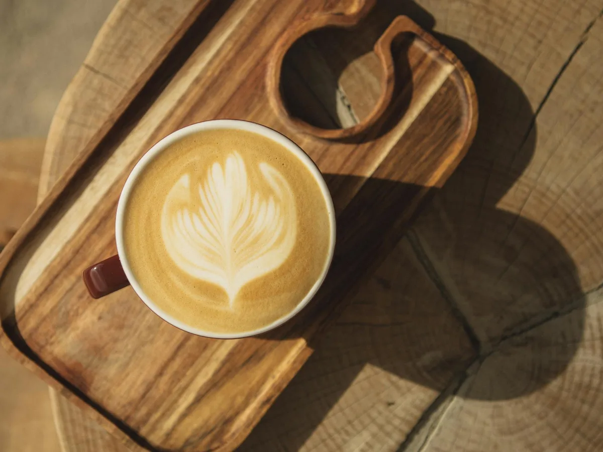 Latte con foglia artistica su vassoio di legno rustico, mattina accogliente