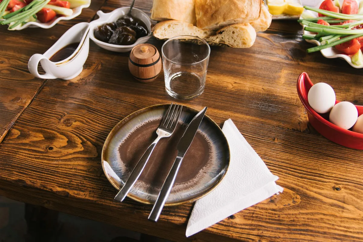 Tavolo rustico con pane, verdure e piatto in ceramica