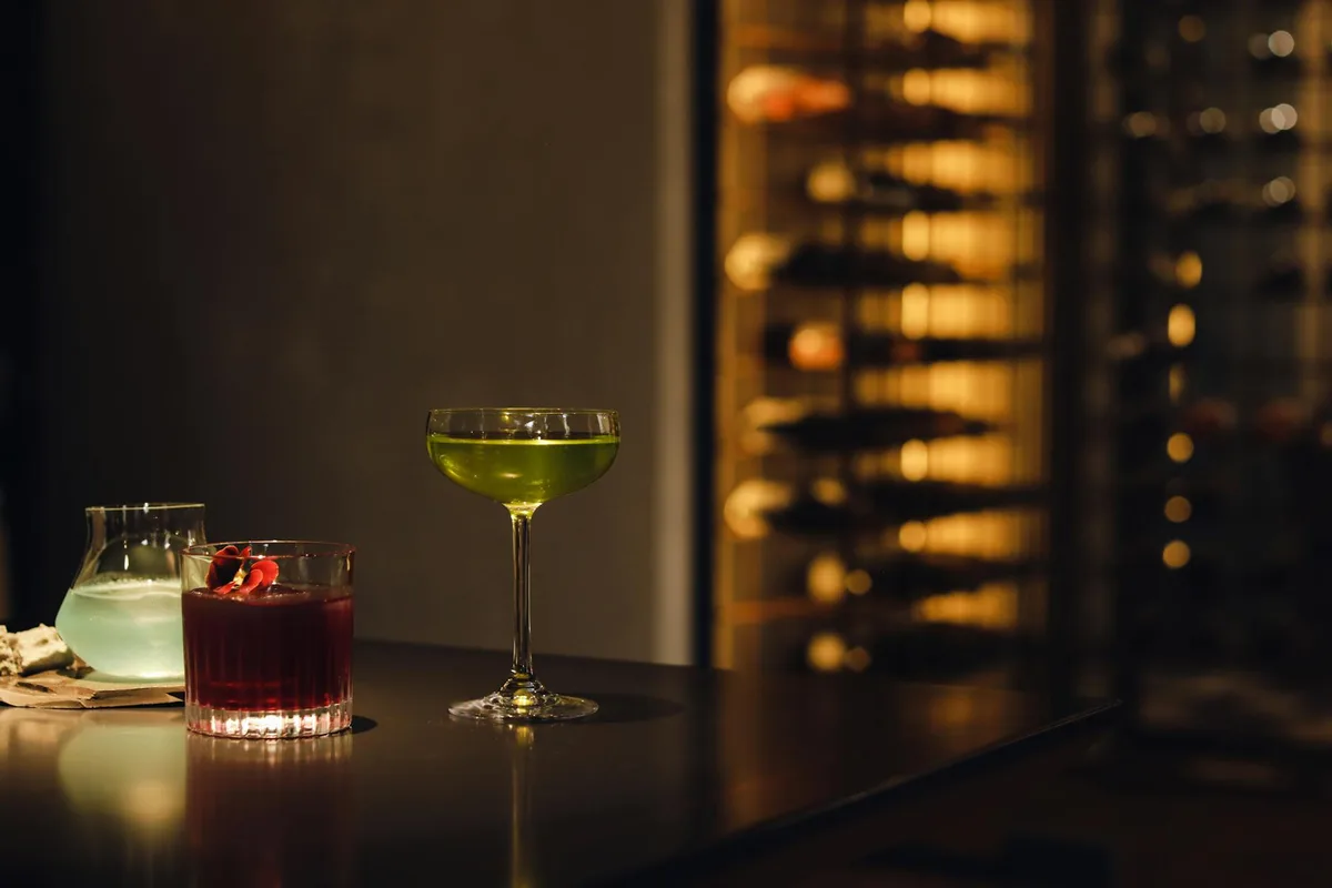 Farbenfrohe Cocktails auf einer Bartheke in gedämpftem Licht, die Luxus und Eleganz ausstrahlen