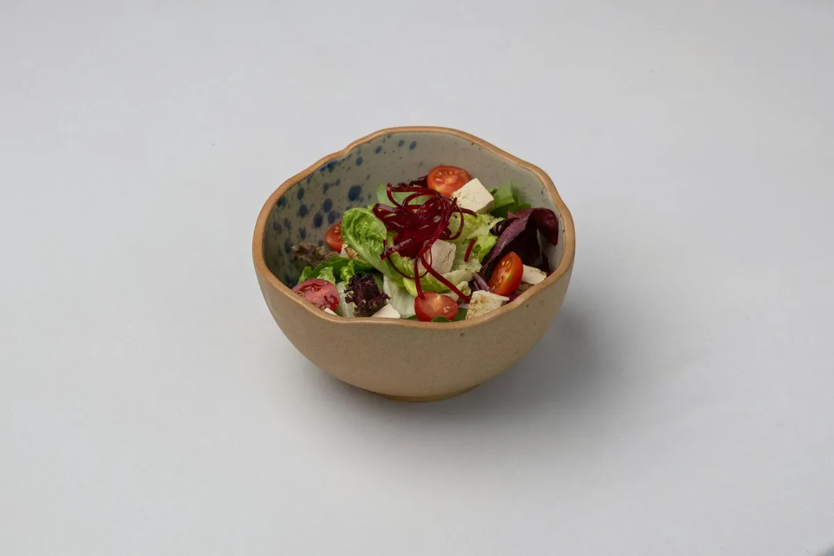Insalata mista con tofu, pomodorini e verdure in ciotola di ceramica