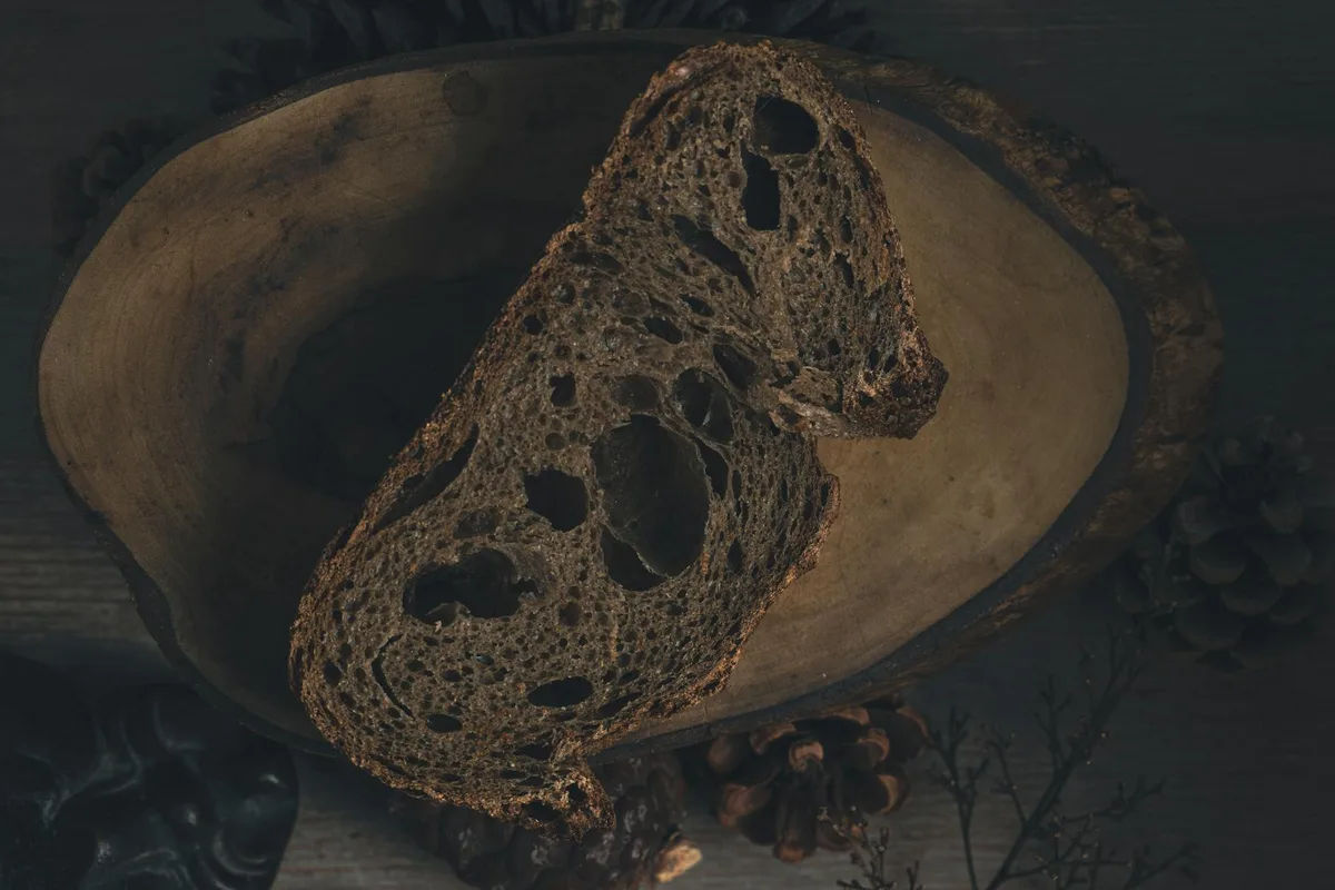 Fetta artistica di pane di segale scuro su piatto di legno rustico