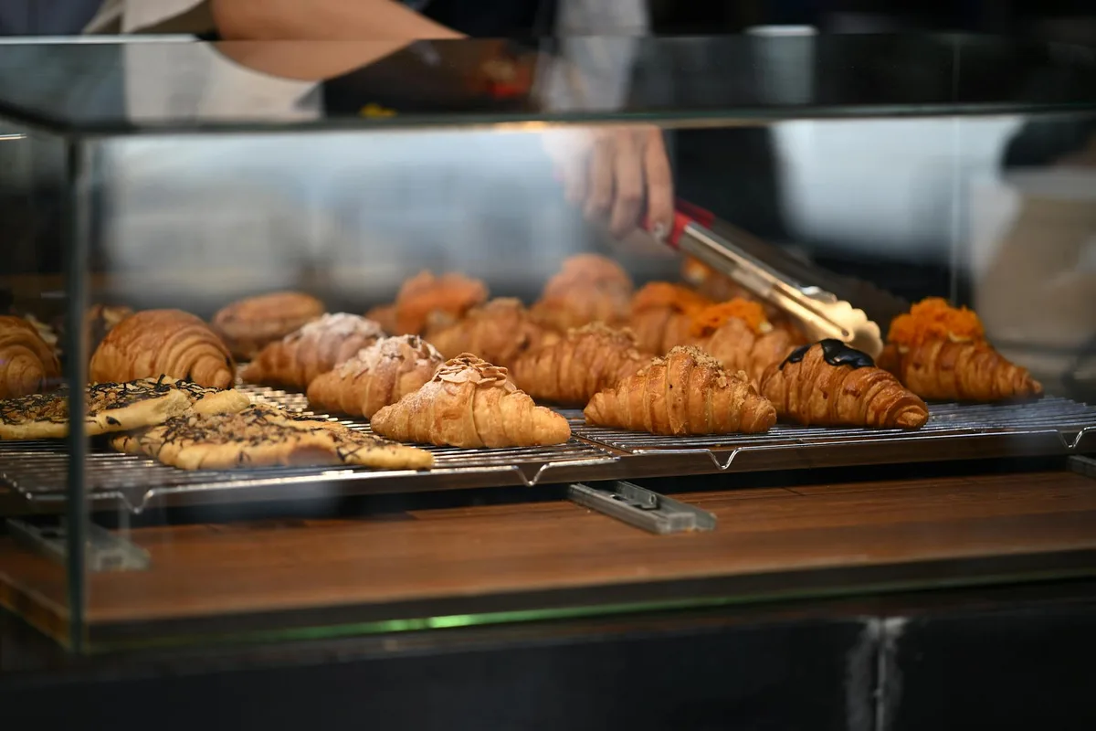 Cornetti assortiti in vetrina con mano che sceglie un pasticcino