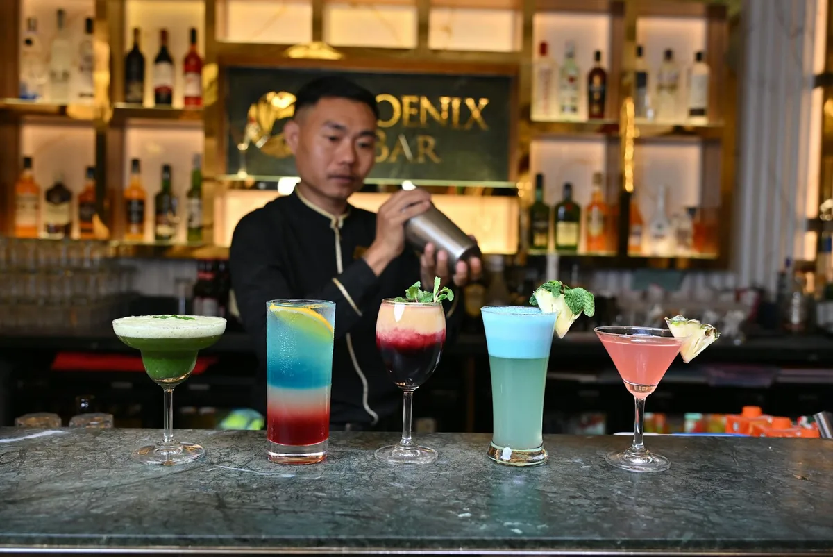 Bartender prepara cocktail colorati al Phoenix Bar di Goa, mixology in ambiente vivace