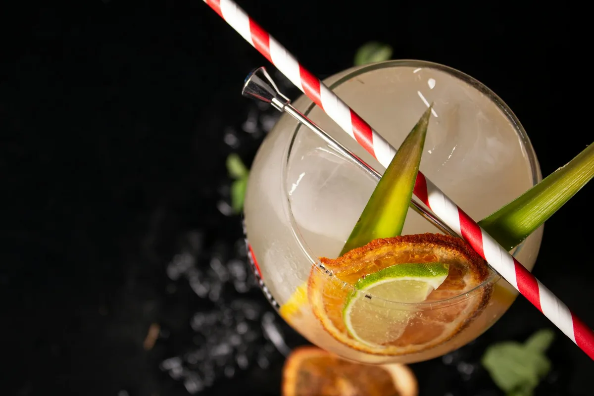 Gros plan d'un cocktail coloré avec agrumes et feuilles tropicales, boisson fraîche