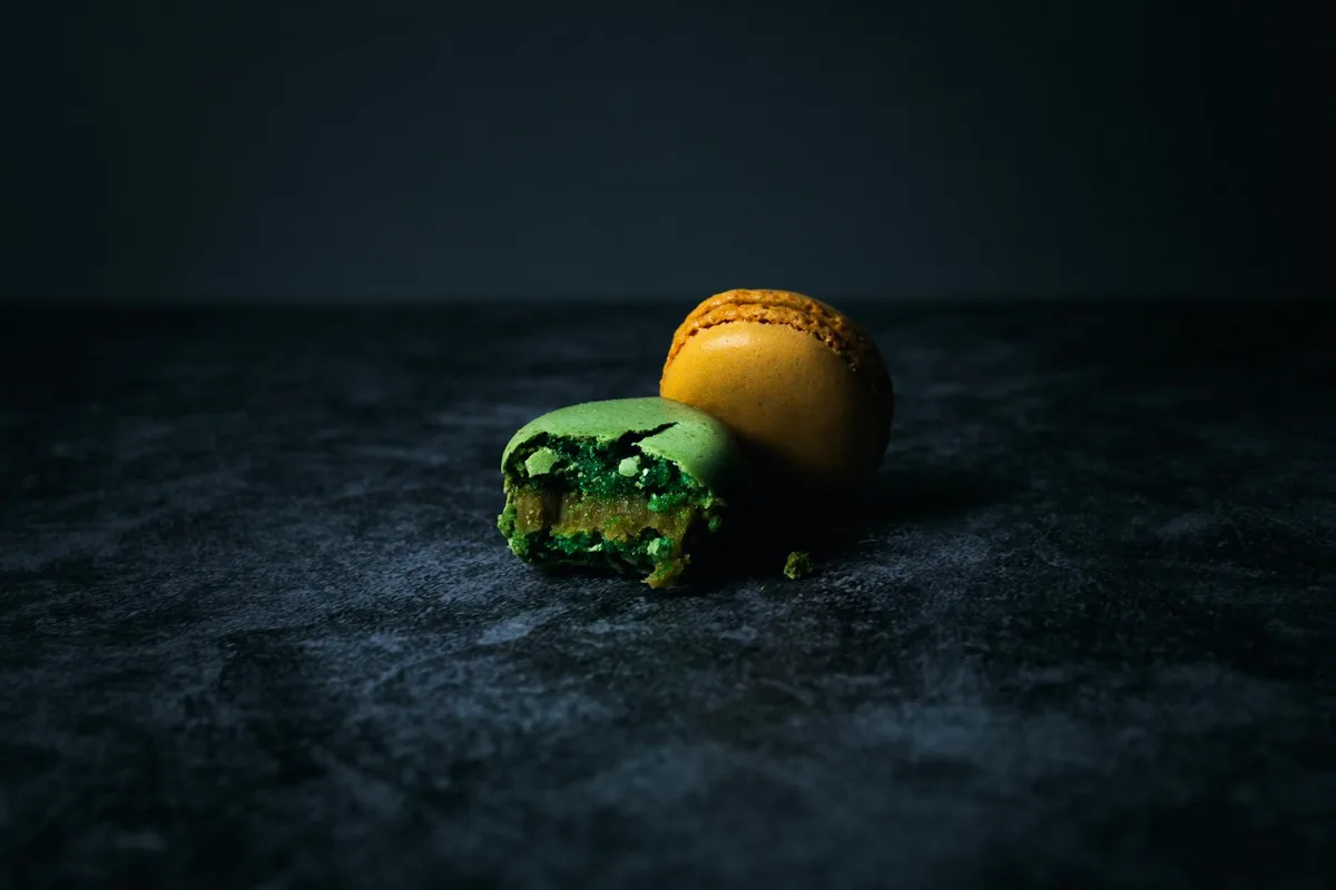 Close-up de macarons coloridos com um mordido em superfície escura