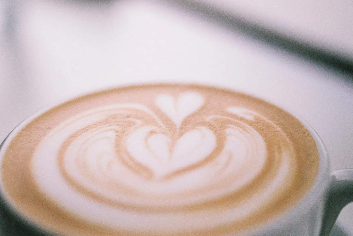 Primo piano di latte art a cuore in tazza di caffè fumante