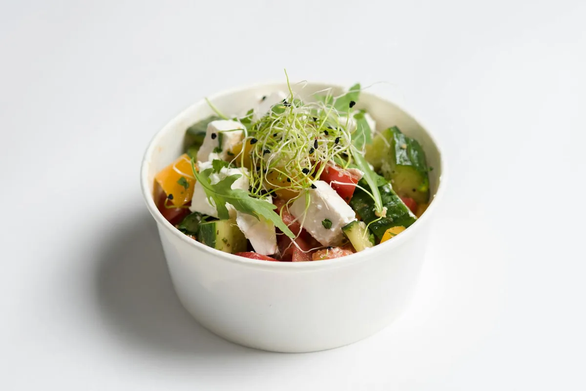 Farbenfroher mediterraner Salat mit Feta, Gurken und Sprossen in einer weißen Schüssel