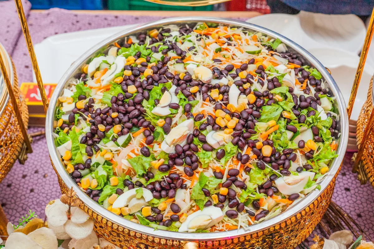 Ensalada colorida con frijoles negros, maíz y repollo en tazón de latón decorativo