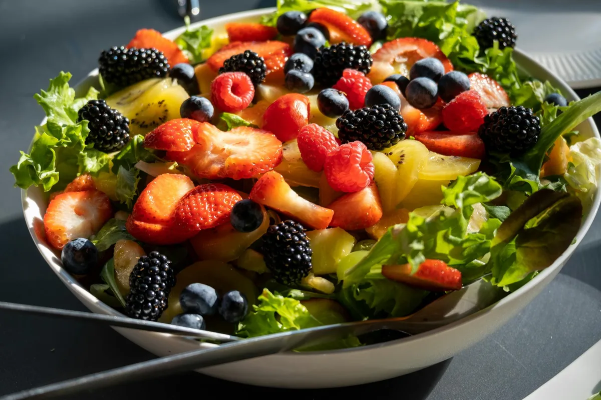 Colorful salad with fresh strawberries, blueberries, and greens, perfect for a healthy lifestyle.