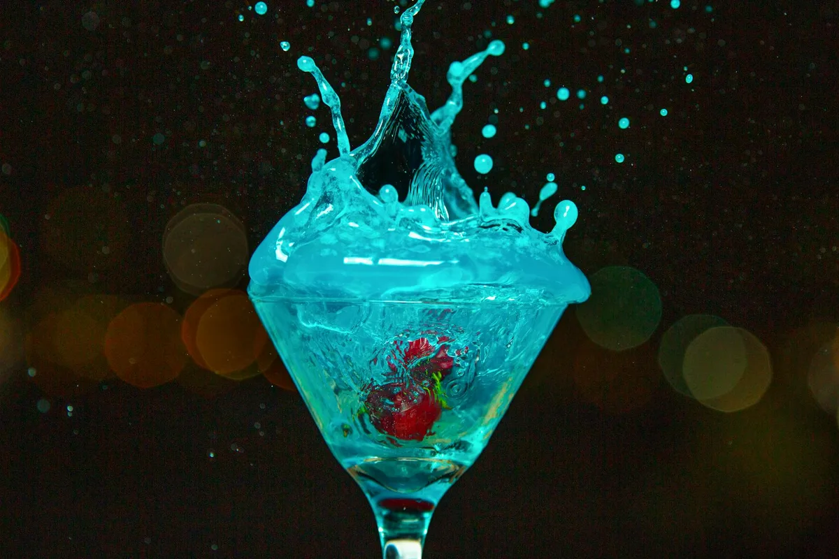 Schizzo dinamico di un cocktail blu in un bicchiere martini con ciliegie