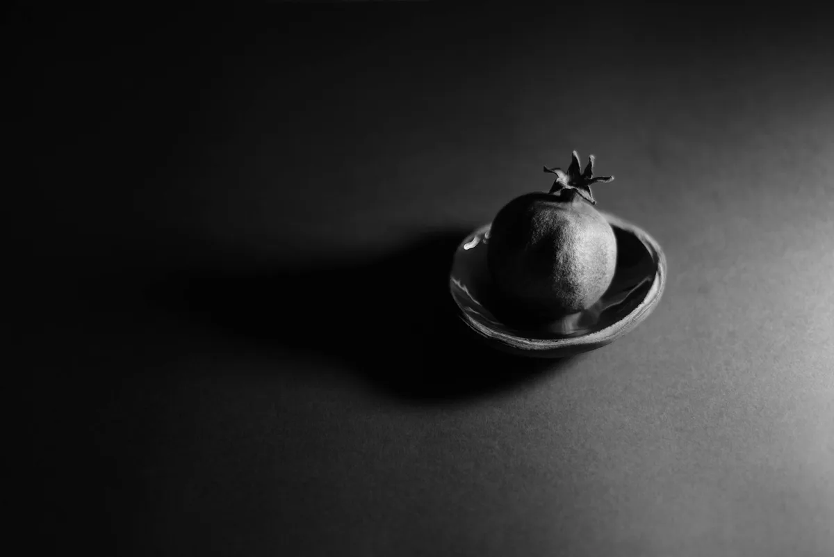 Foto elegante em preto e branco de romã em prato com iluminação dramática