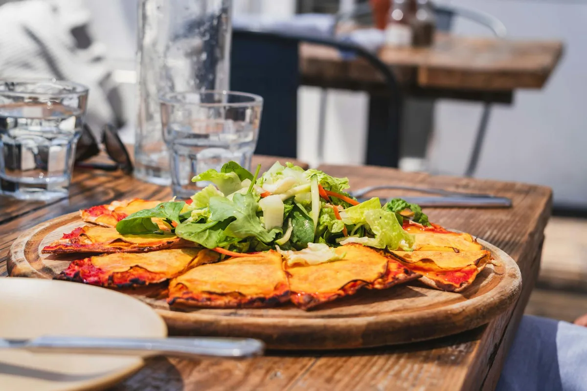 Köstliche dünne Krustenpizza mit frischem Grün im Malibu-Café genießen