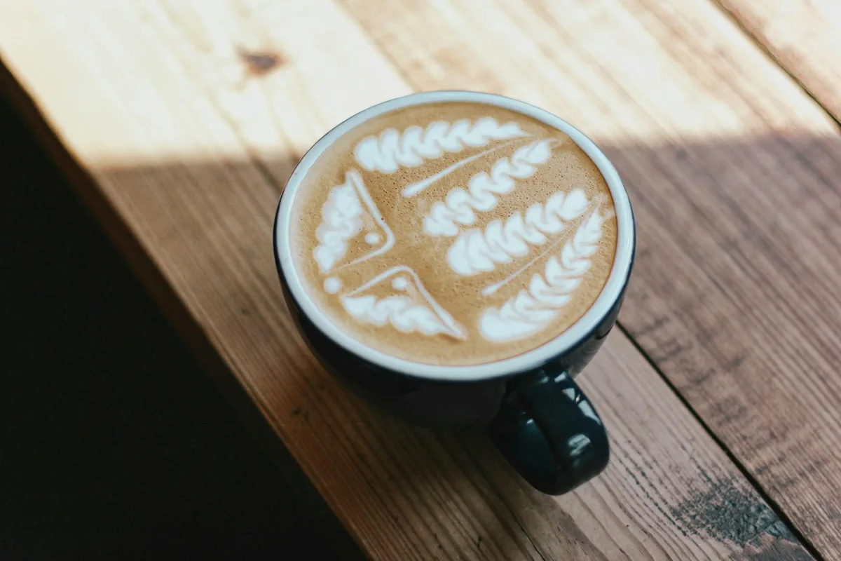 Latte con schiuma artistica su tavolo rustico in legno, palette di colori
