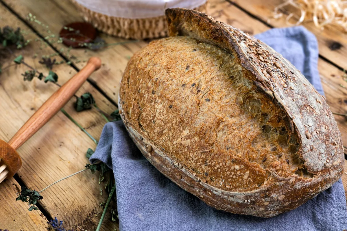 씨드가 토핑된 갓 구운 사워도우 빵, 러스틱 우드 테이블 세팅