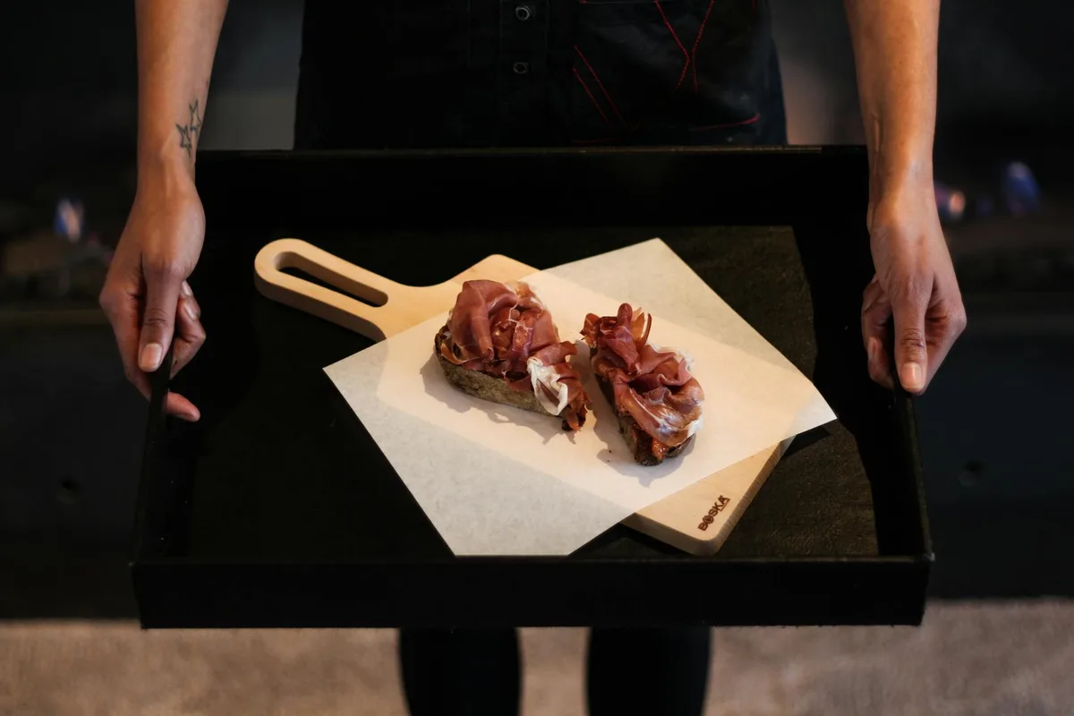 Mãos apresentando tábua de frios gourmet para conceitos gastronômicos