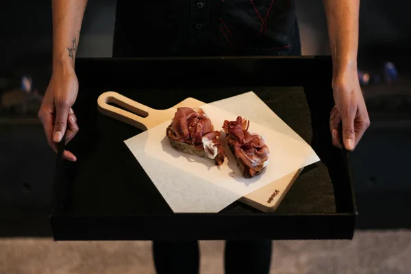 Mani che presentano un tagliere di salumi gourmet, concetti food e lifestyle