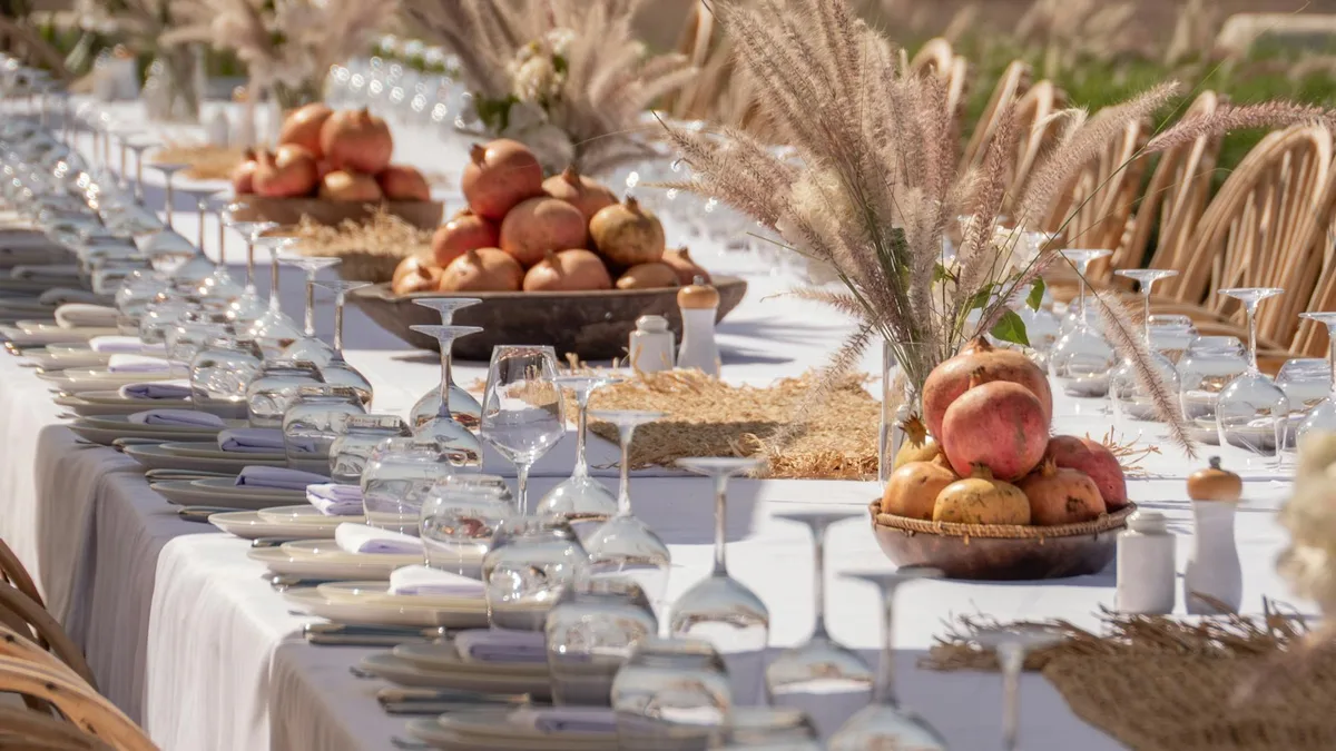 Lange Festtafel mit Granatäpfeln und Gläsern für eine Outdoor-Feier
