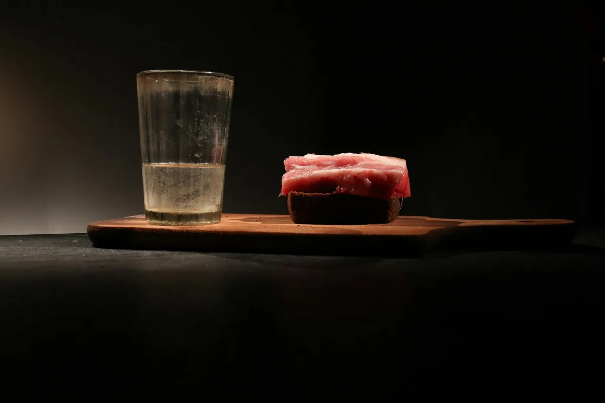 나무 도마 위 유리잔과 고기 빵의 무디한 정물