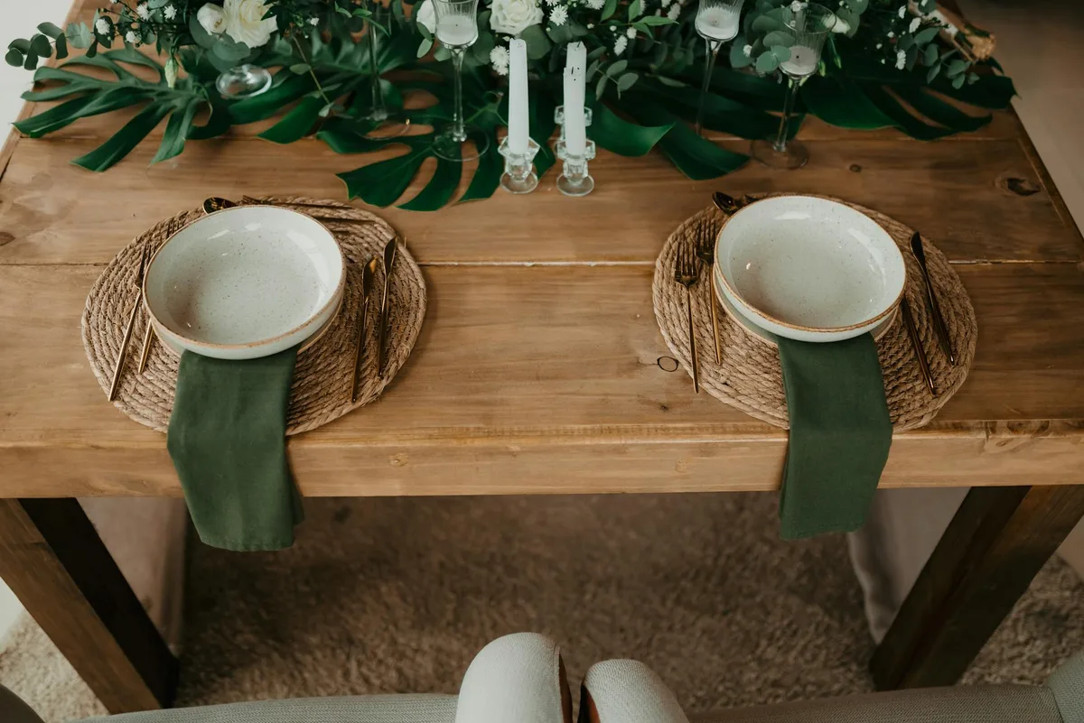 Tavolo da pranzo rustico con decorazioni verdi e mise en place elegante per due