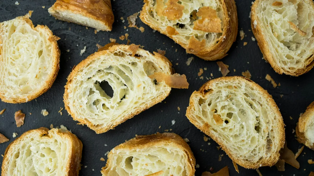 Vista dall'alto di cornetti a fette su superficie nera con briciole