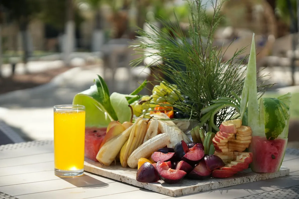 Lebhafter tropischer Obstteller im Freien mit Orangensaft und Sonne