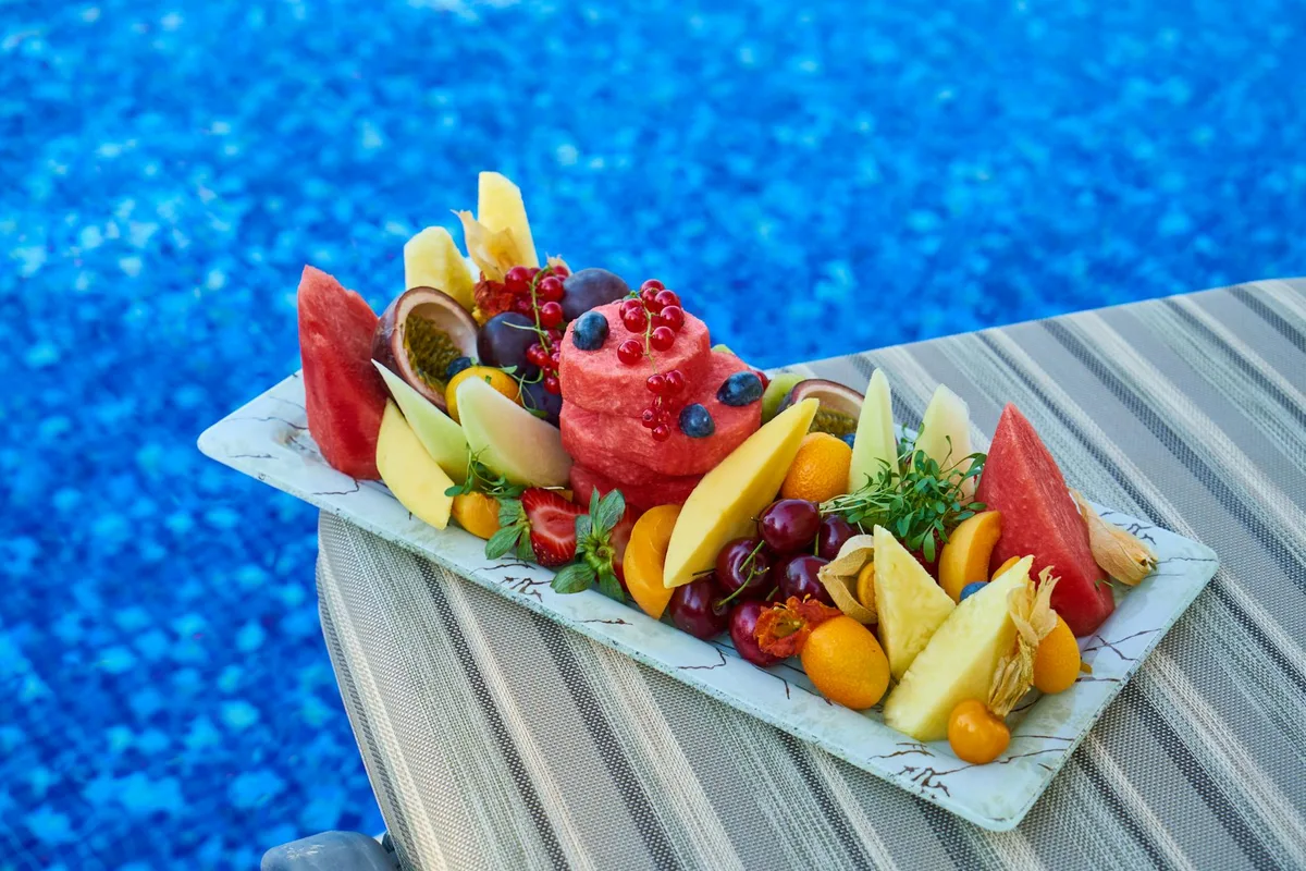Piatto di frutta tropicale vibrante con assortimento delizioso a bordo piscina blu