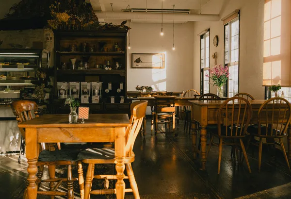 Warm beleuchtetes Café mit Holzmöbeln und Pflanzen bei Sonnenuntergang