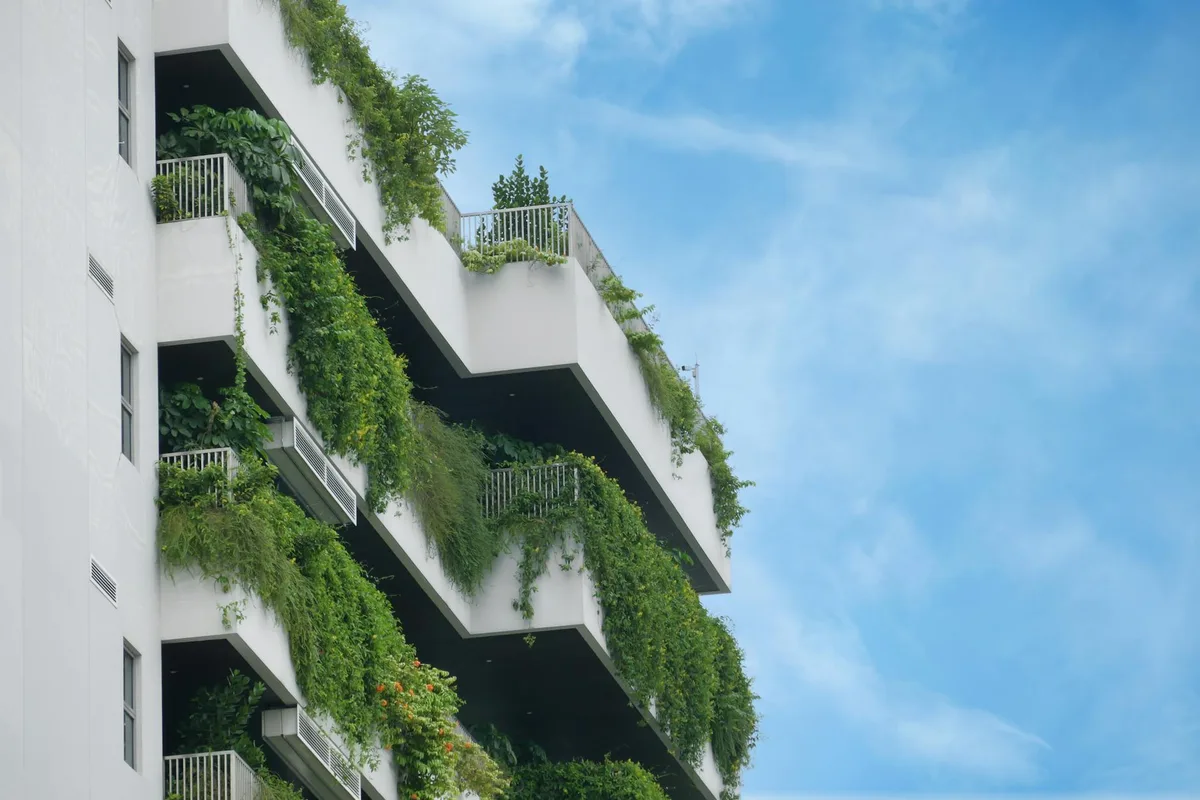 Edificio residenziale con giardini verticali lussureggianti su balconi, cielo azzurro