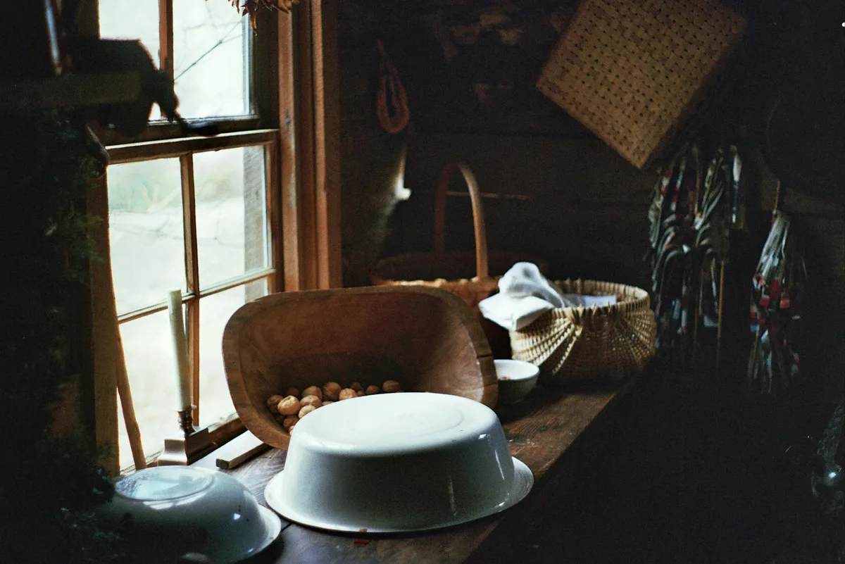 Cucina rustica con ciotole in legno e cesti vicino a una finestra, atmosfera accogliente