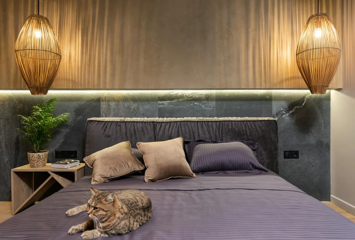 Ruhiges Schlafzimmer mit entspannter Katze, eleganter Beleuchtung und weichen Kissen