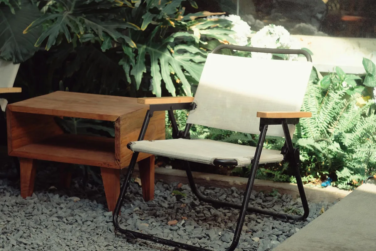 Giardino sereno con sedia e tavolo in legno tra piante verdi rigogliose, relax all'aperto