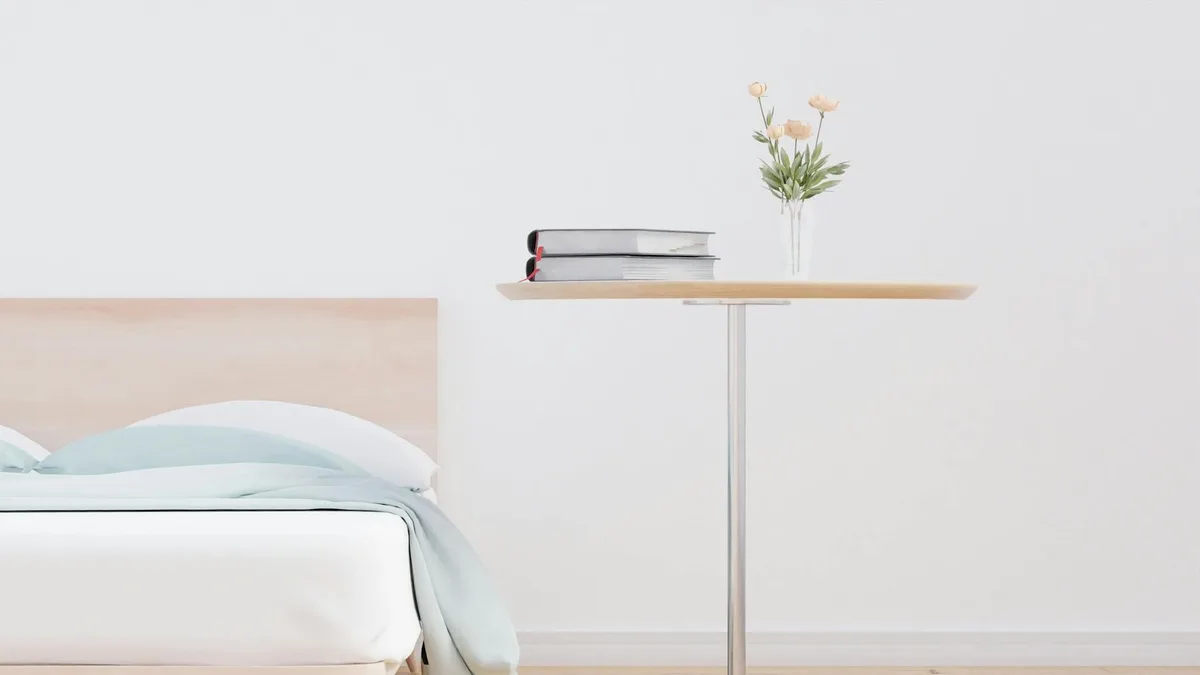 Dormitorio minimalista sereno con mesa de madera, libros y jarrón con flores