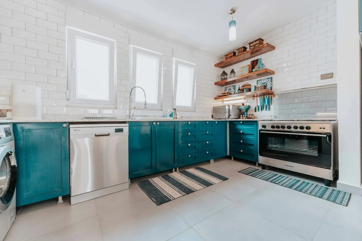 Cucina moderna luminosa con mobili blu, elettrodomestici acciaio e scaffali aperti