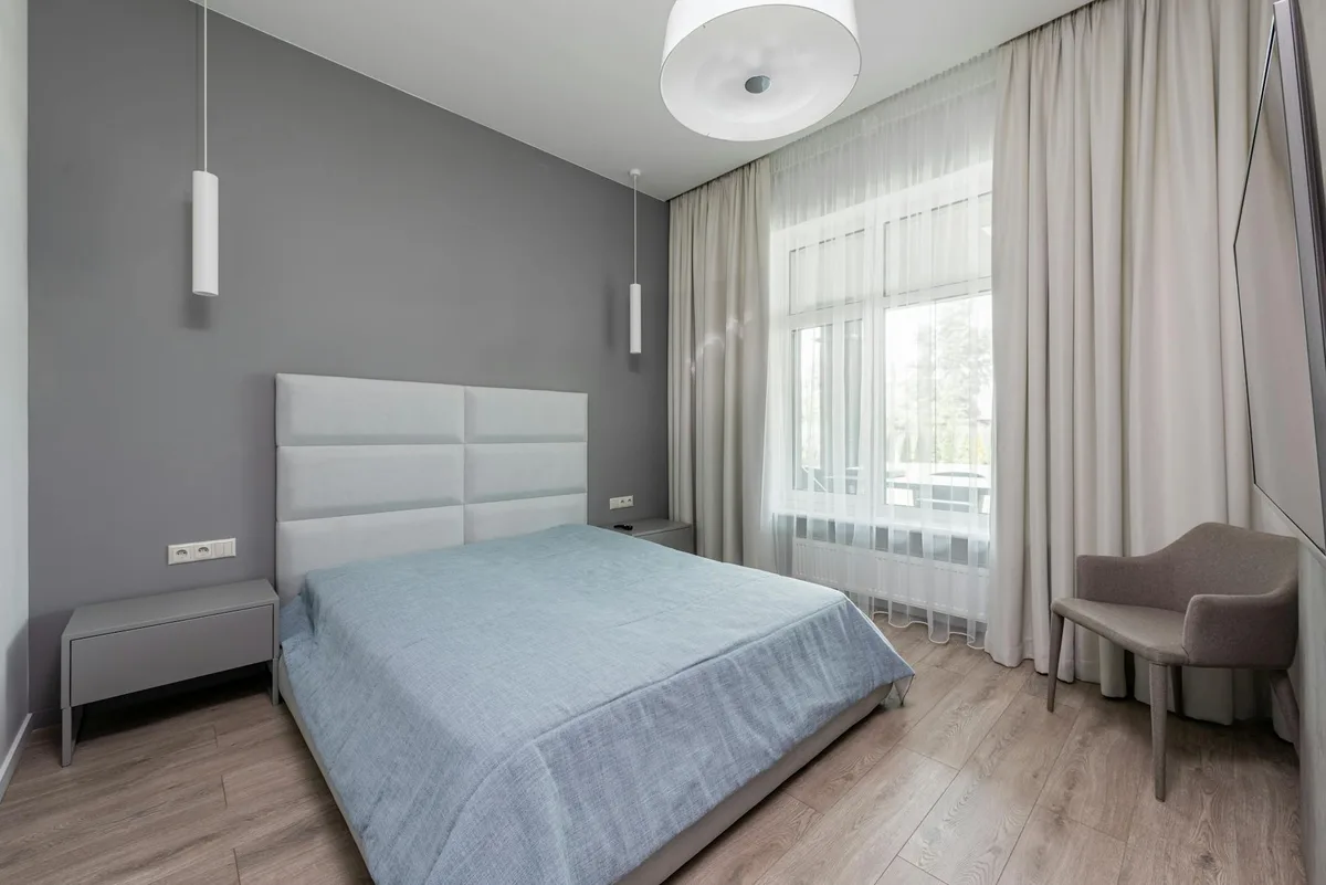 Komfortables zeitgenössisches Schlafzimmer mit weichem Sessel und Bett am Tag