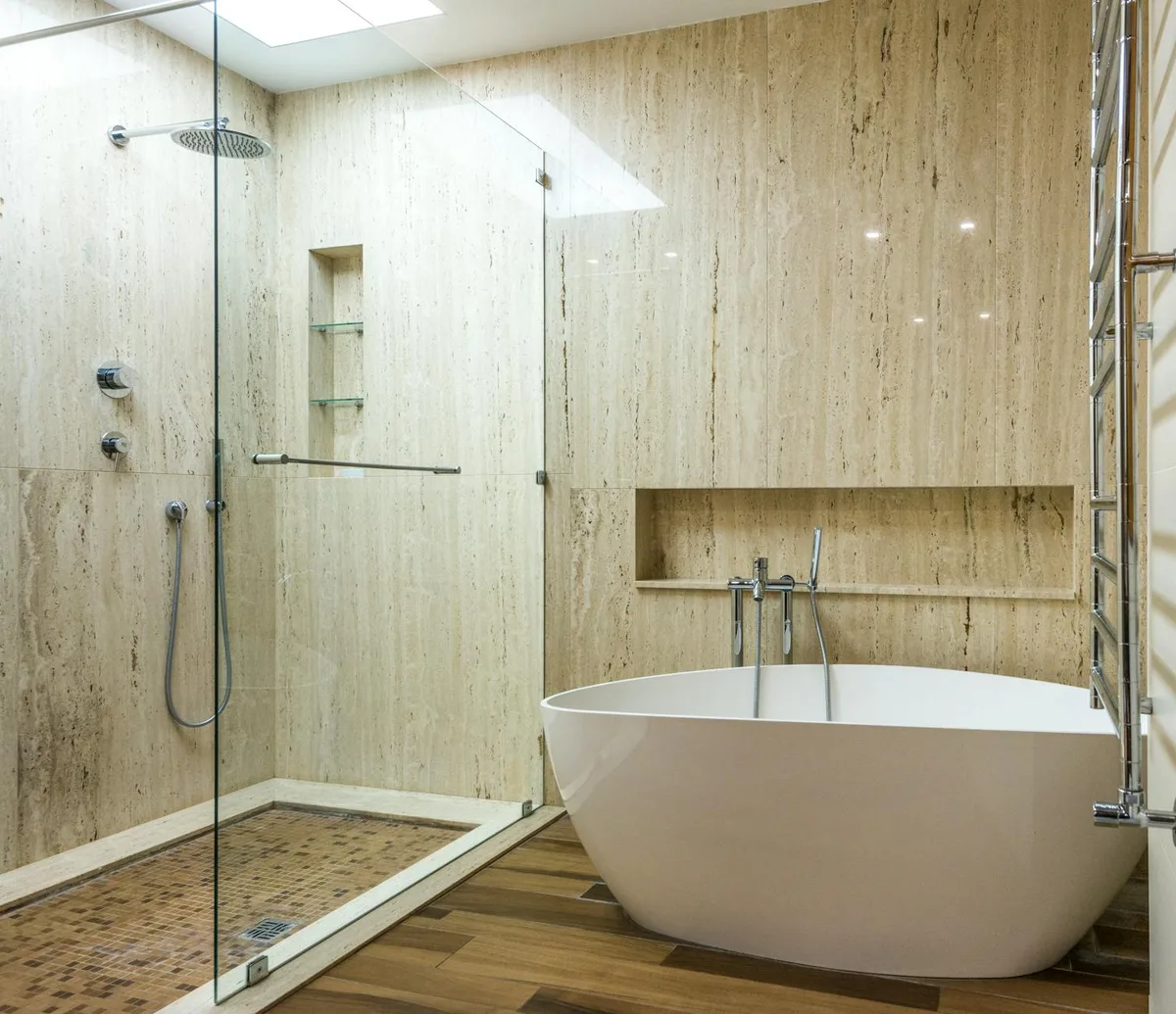 Bagno moderno con parete in marmo, doccia in vetro e vasca elegante