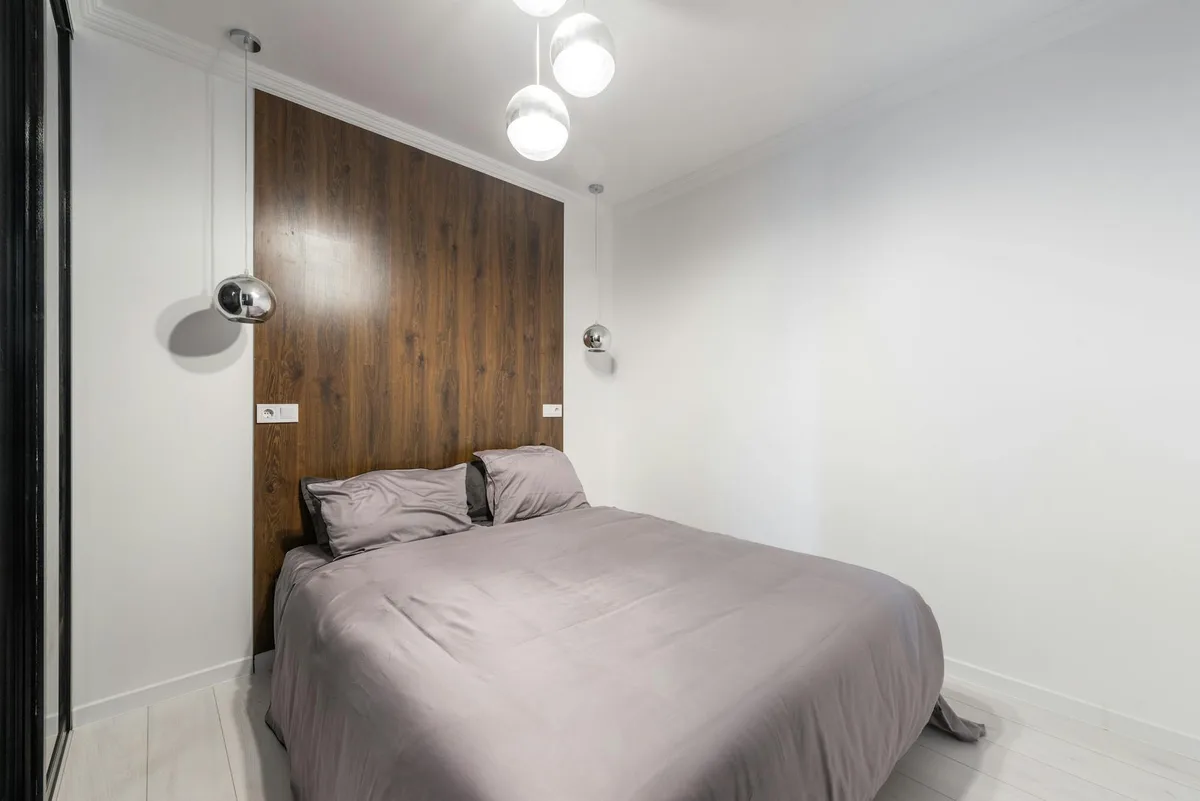 Camera da letto moderna con design minimal, accenti in legno e lampade a sospensione