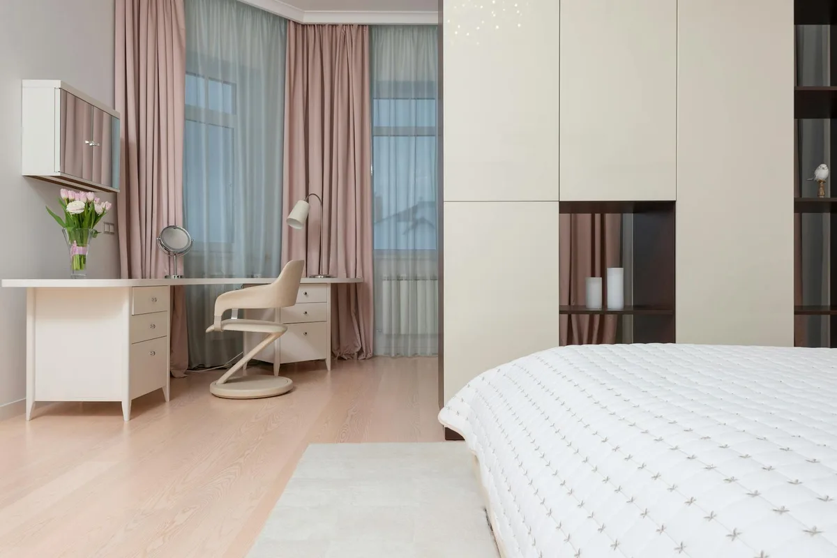 Modernes Interieur eines großen Schlafzimmers mit weißem Kleiderschrank und weichem Bett