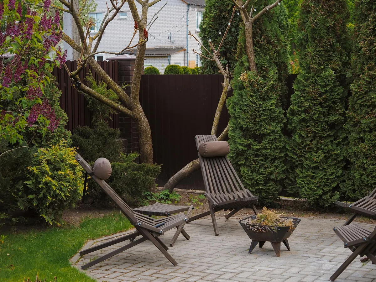 Gemütlicher Hinterhof mit Holzliegen und üppigem Grün für Entspannung