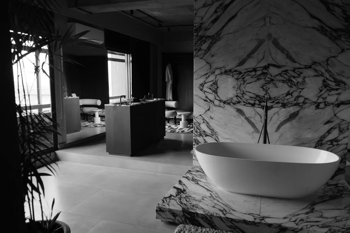 Baño elegante con bañera exenta y paredes de mármol en tonos monocromos