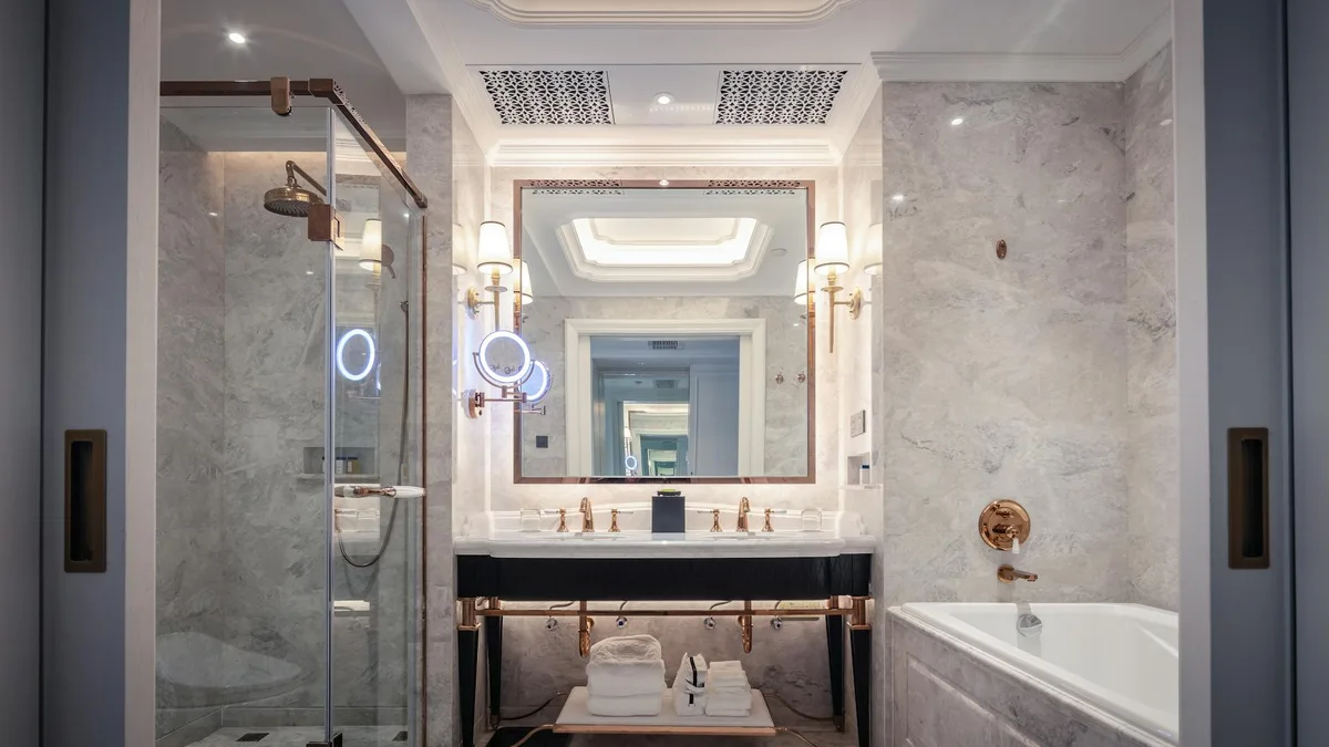 Salle de bain élégante avec lavabo en marbre, baignoire et miroir sous un éclairage ambiant