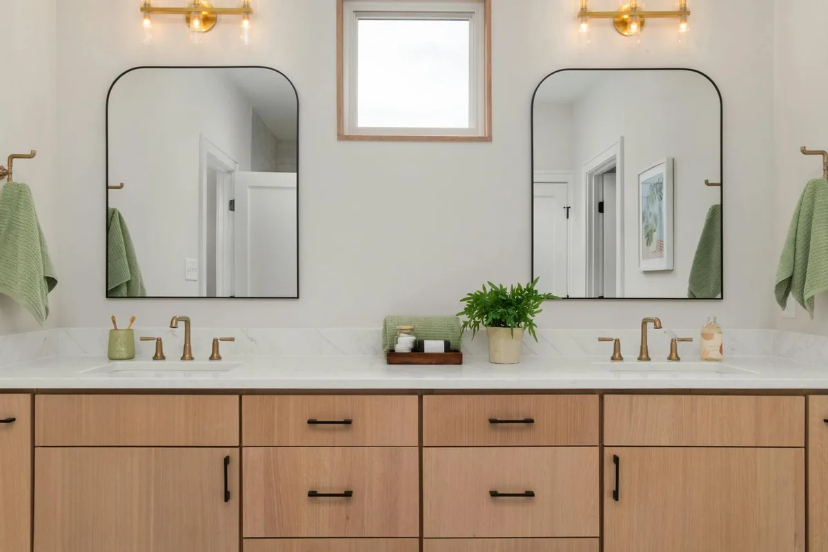 Elegantes Badezimmer mit Doppelwaschbecken, Spiegeln und warmem Licht – modernes Design mit Holzschränken