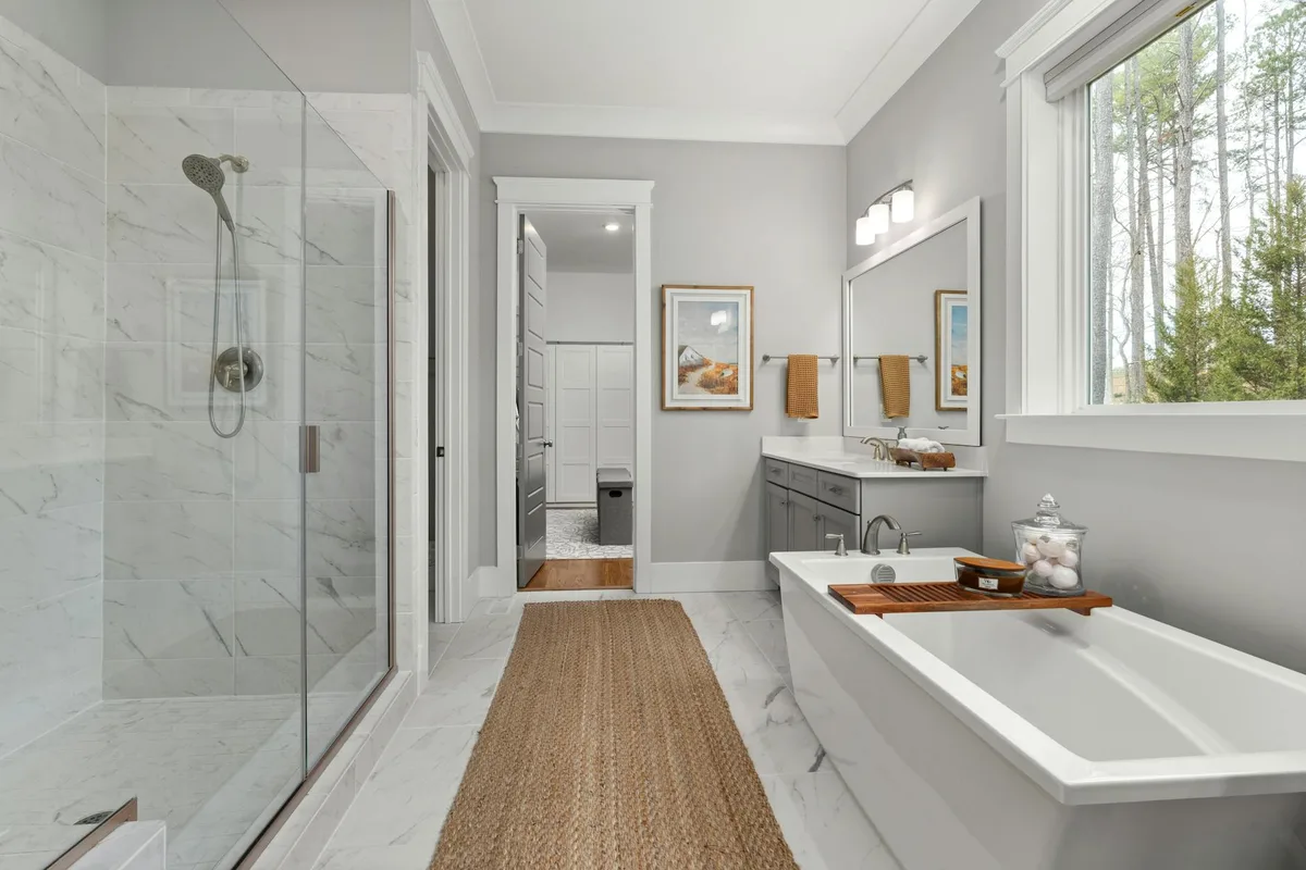 Elegantes Badezimmer mit freistehender Badewanne, Glasdusche und großem Fenster mit Ausblick